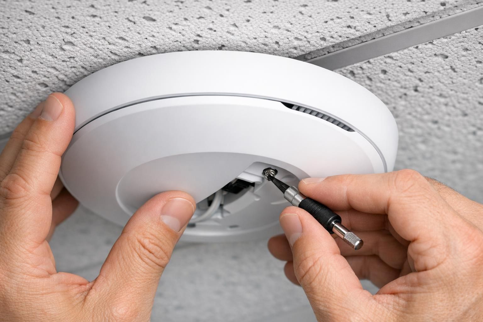 Technicien fixant une borne Wi-Fi professionnelle au plafond d'un bureau